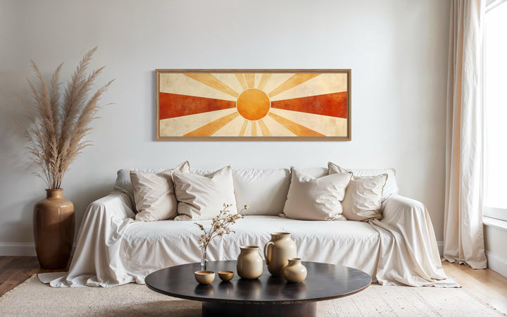 Mid century modern sun rays long horizontal wall art in a wood frame above a white sofa.