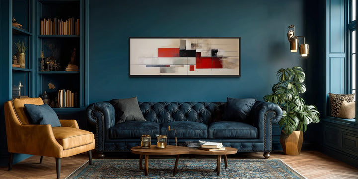 Large abstract geometric canvas print in red, beige, and black over a blue tufted sofa.