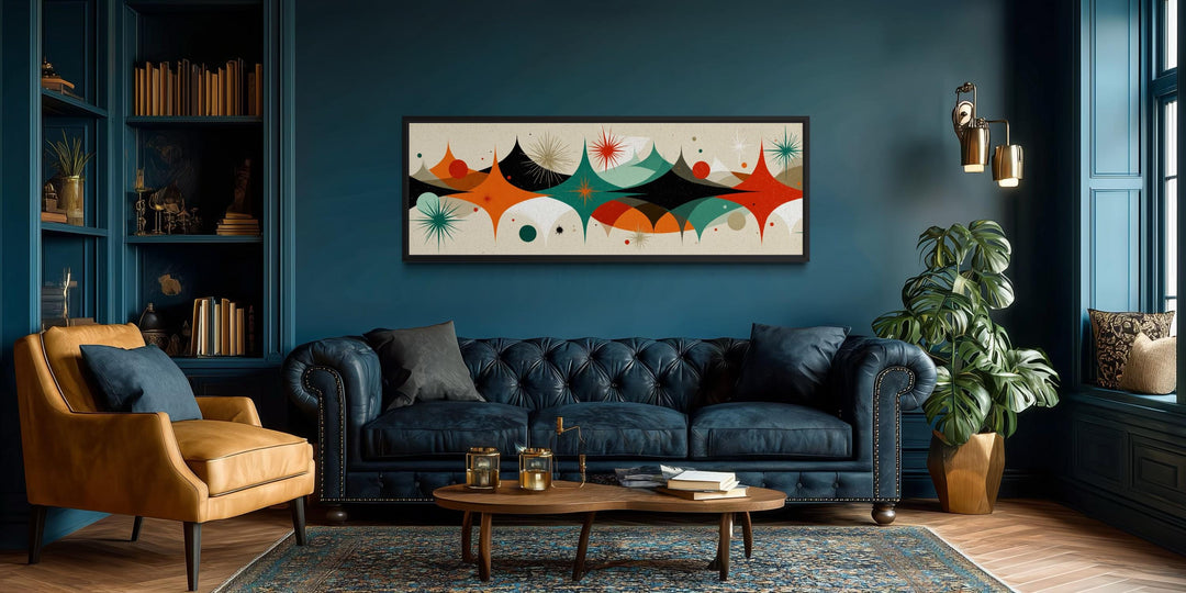 Long horizontal canvas print with a mid-century modern atomic starburst design above a blue sofa.