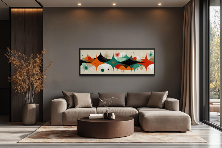 Mid century modern horizontal canvas print with atomic starburst design above a neutral sofa.