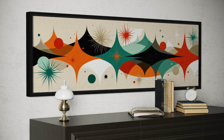 Mid century modern long horizontal canvas print with an atomic starburst design above a sideboard.