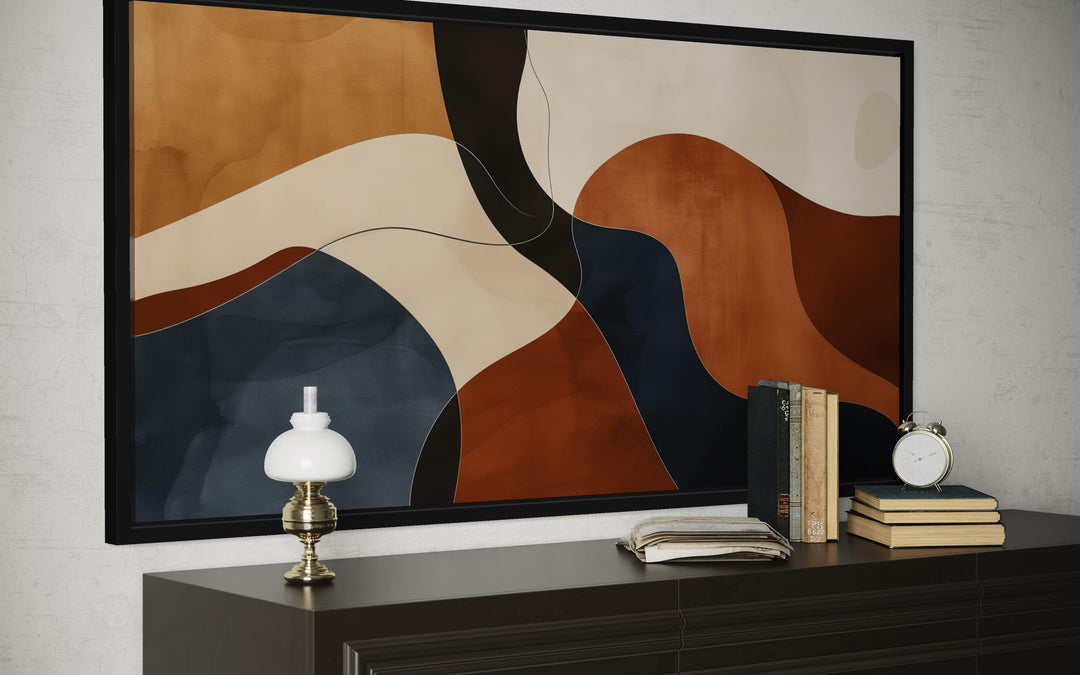 Mid Century abstract canvas print with curved shapes in rust, navy, and beige above a dark credenza.