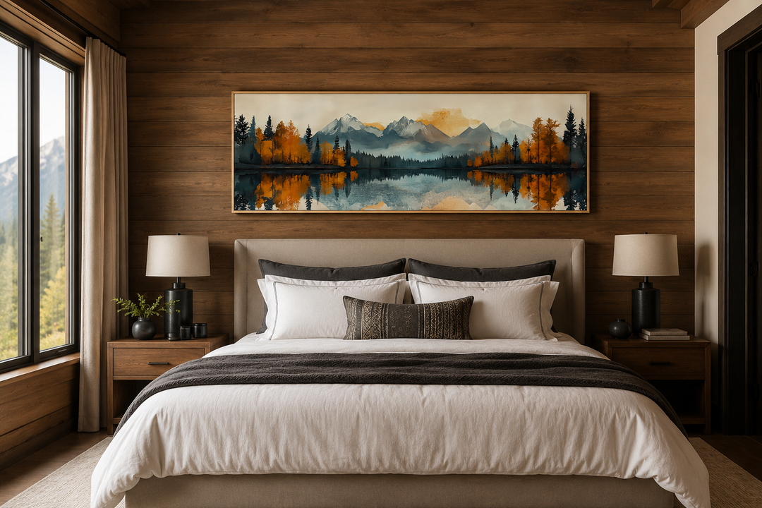 Long narrow canvas wall art of a mountain lake landscape above a bed in a wood-paneled bedroom.
