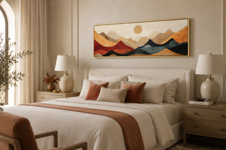 Long horizontal mid-century modern mountain canvas wall art in a gold frame above a bed.