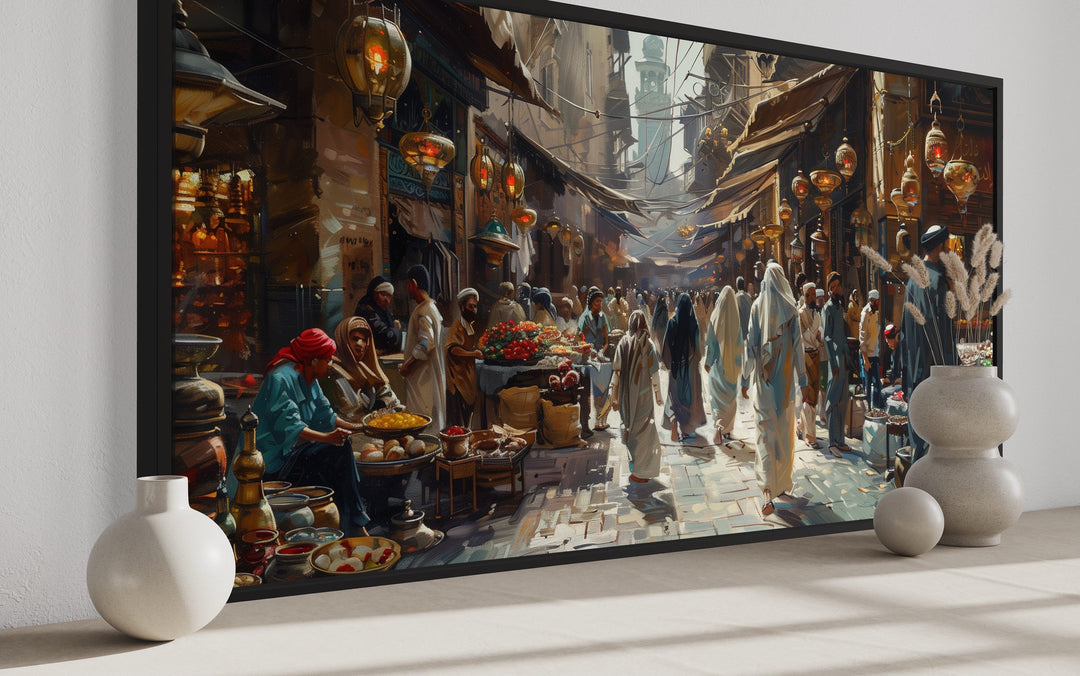 Framed canvas wall art of a bustling Middle Eastern bazaar with people, lanterns, and fruit stalls.