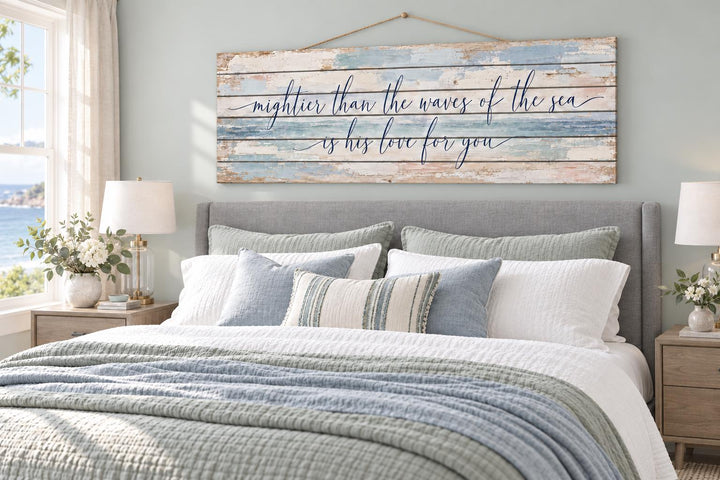 Mightier Than the Waves of the Sea distressed wood wall art hanging above a bed in a coastal room.