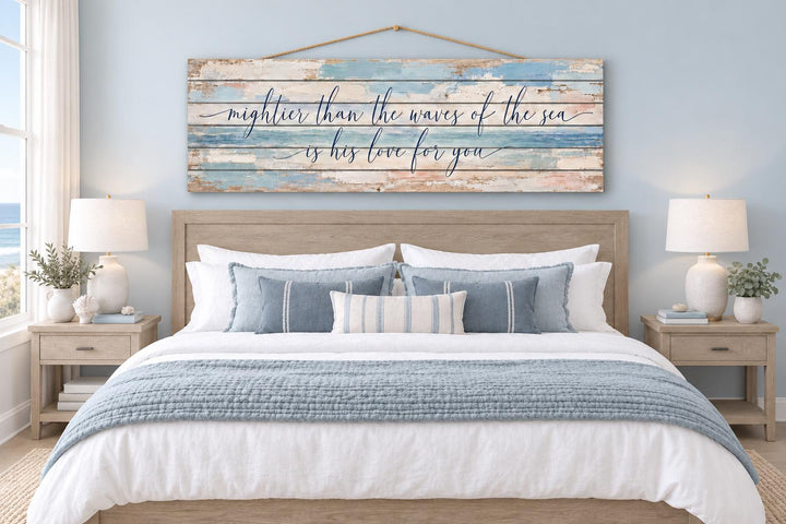 Mightier Than the Waves of the Sea distressed wood wall art hanging above a bed in a coastal room.