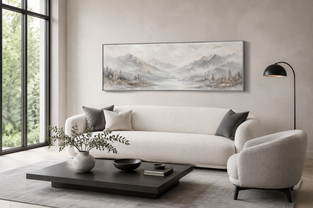 Minimalist abstract mountain panoramic wall art in grey, silver, and white above a white sofa.