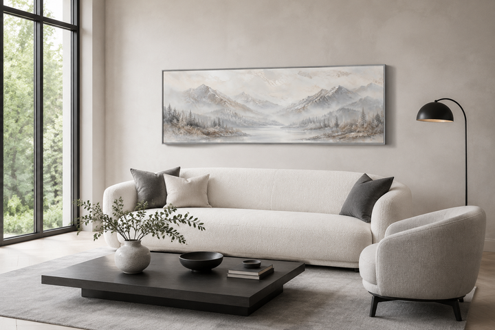 Minimalist abstract mountain panoramic wall art in grey, silver, and white above a white sofa.
