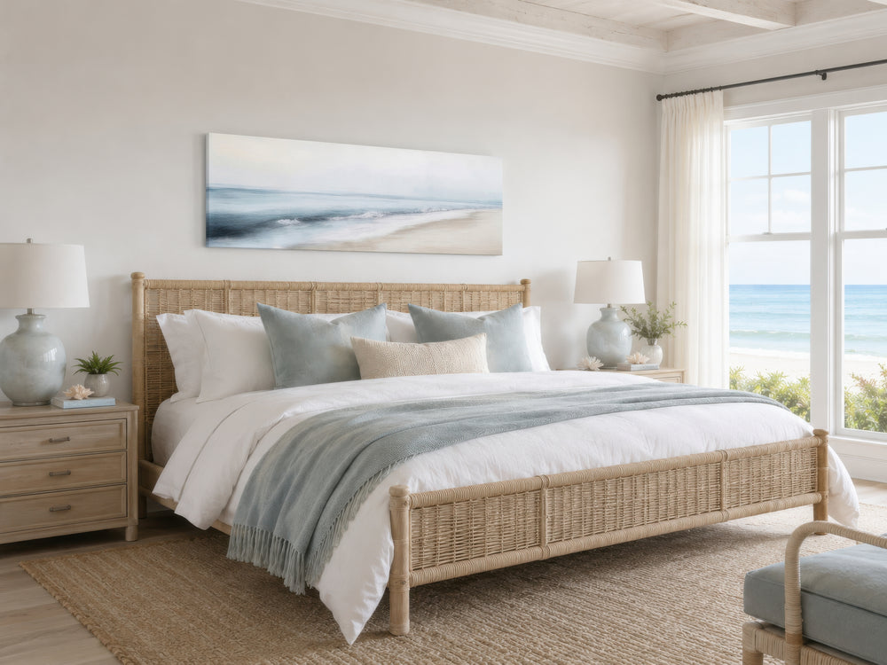 Minimalist coastal gray blue watercolor panoramic ocean beach painting above a woven bed frame.