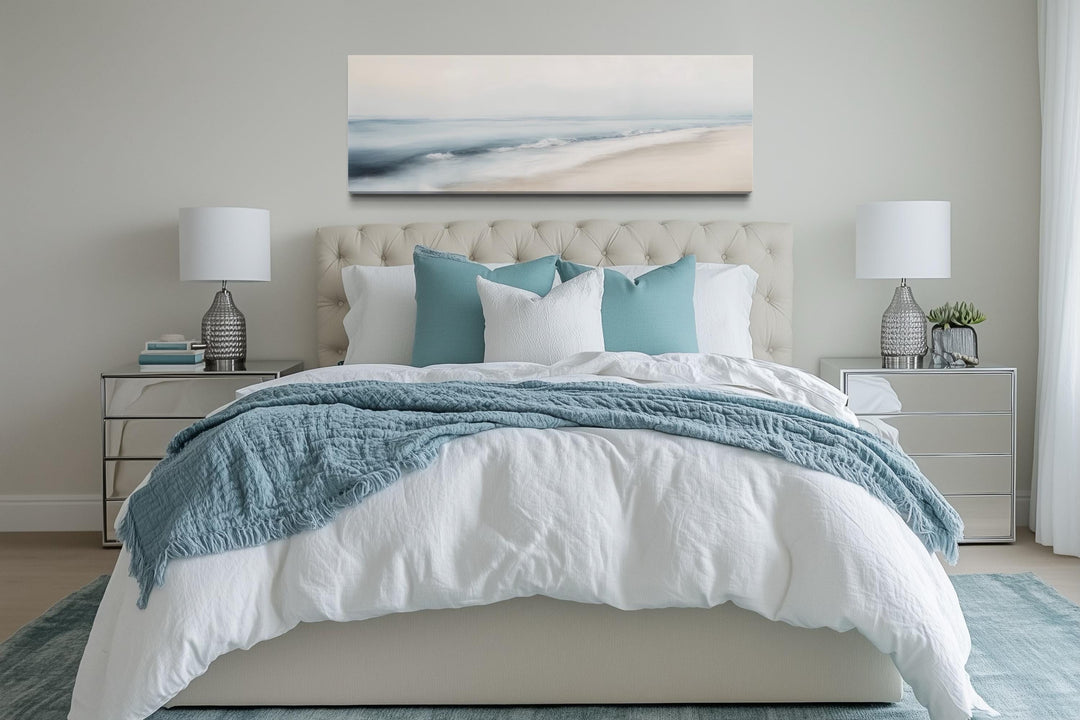 Minimalist coastal gray blue watercolor panoramic ocean beach wall art above a bed.