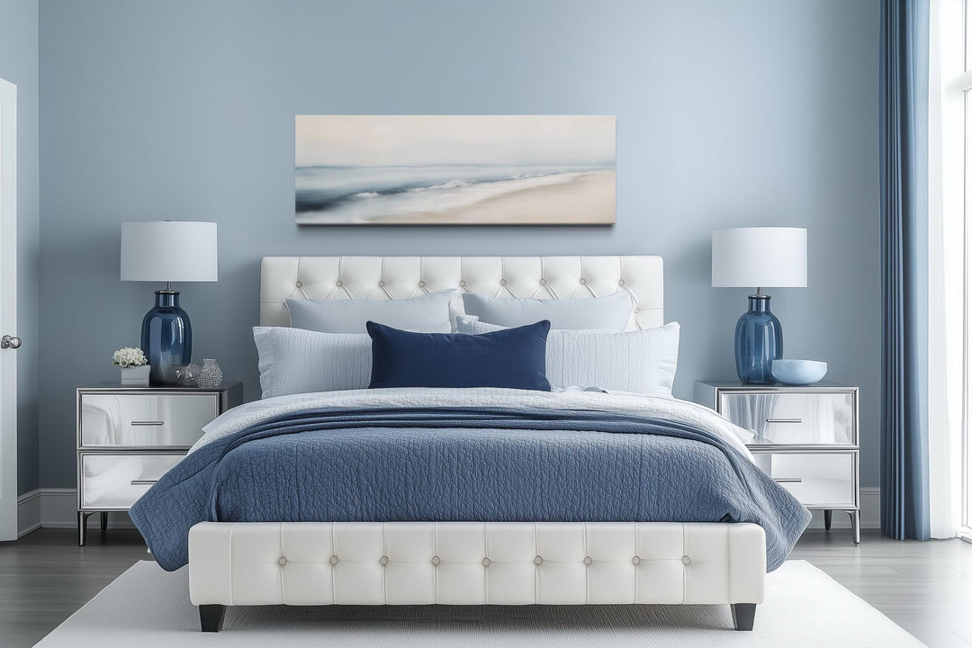 Minimalist panoramic coastal watercolor painting of a gray and blue ocean beach above a bed.