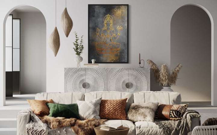 Minimalist Lakshmi gold and silver framed canvas wall art above a white sideboard in a living room.