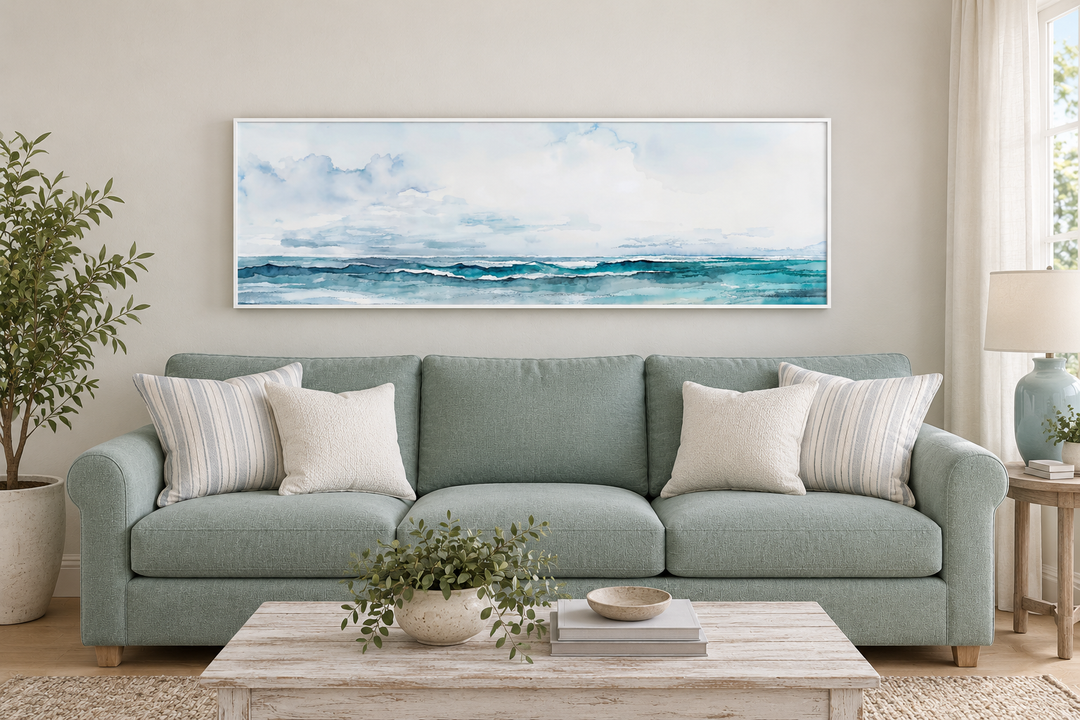 Minimalist horizontal framed canvas wall art of a blue and gray ocean scene over a seafoam sofa.
