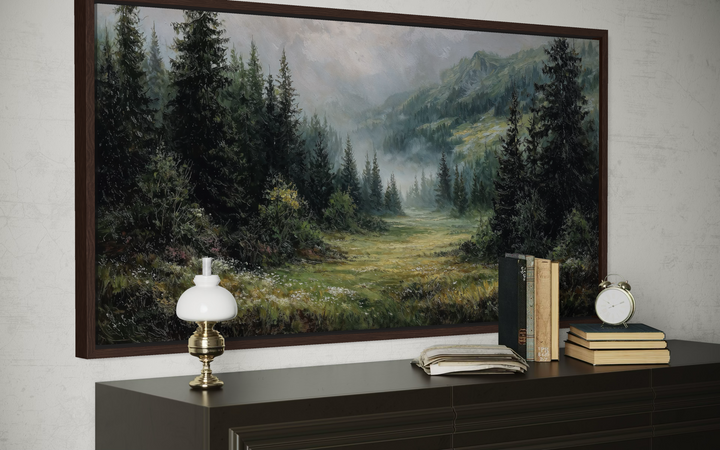 A panoramic canvas painting of a misty mountain meadow and pine forest in a dark wood frame.