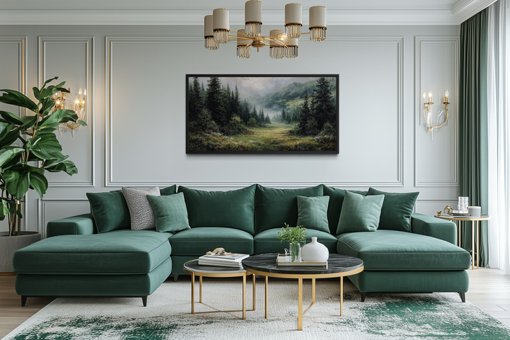 Misty mountain meadow and pine forest canvas wall art in a black frame above a green sectional sofa.