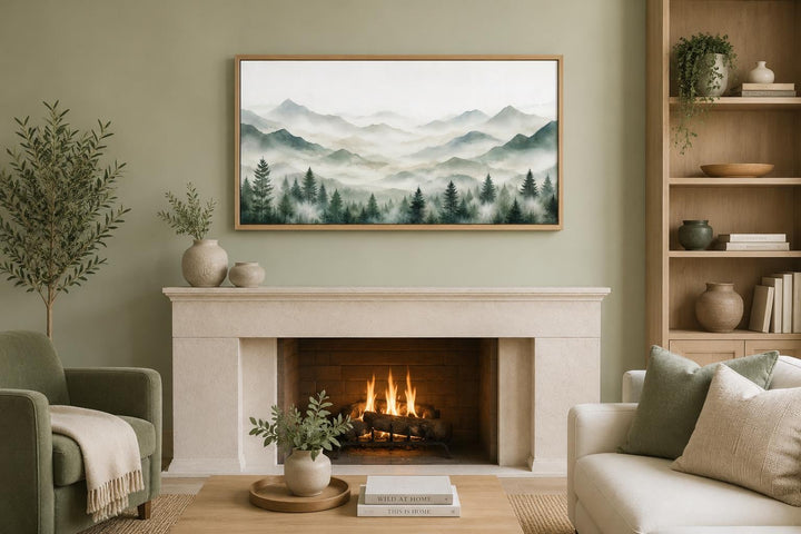 Misty mountain painting with sage green pine trees in a wood frame above a stone fireplace.