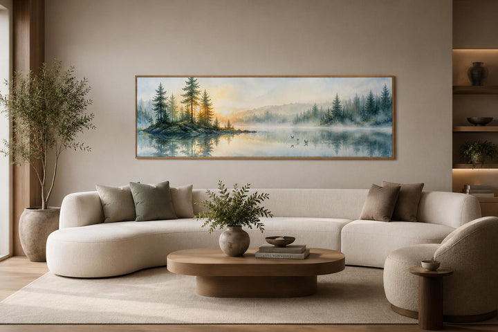Panoramic misty pine forest and lake canvas print hanging above a modern curved sofa.