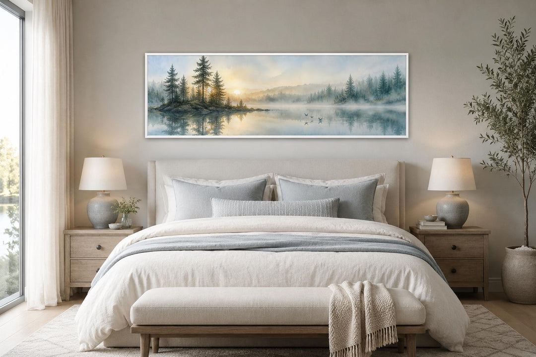 Panoramic misty pine forest and lake canvas wall art hanging above a bed in a neutral bedroom.