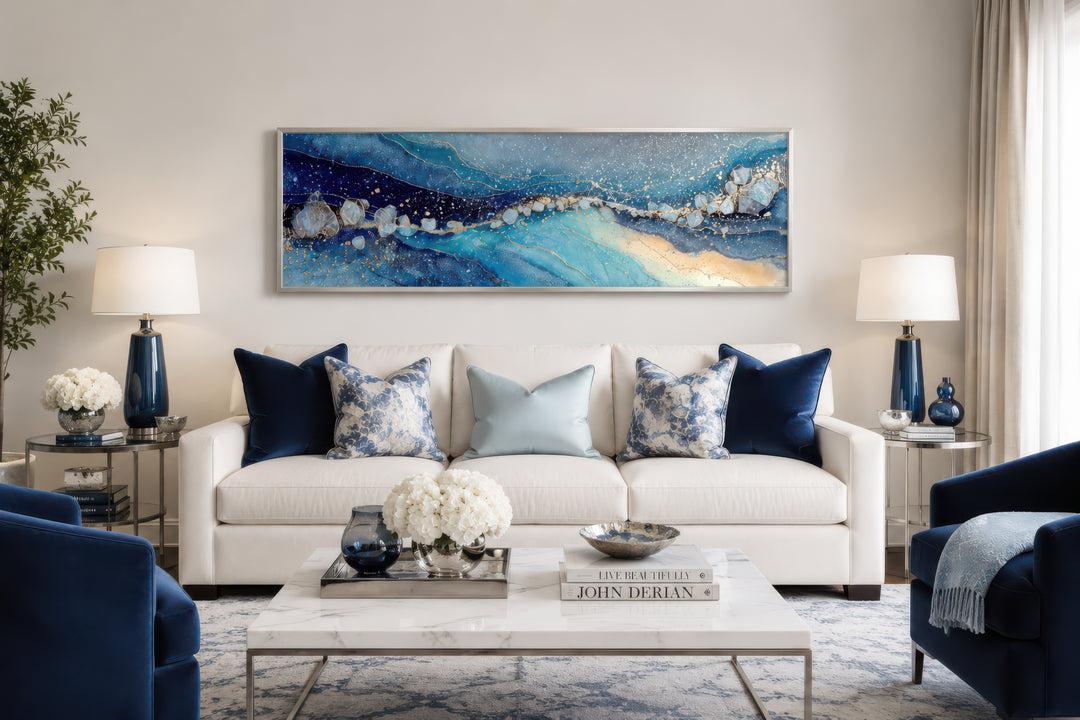 Modern long horizontal blue and navy abstract canvas art hanging above a white sofa.