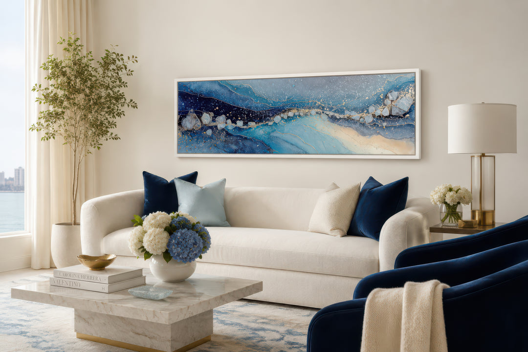 Modern long horizontal blue and navy abstract canvas art hanging above a white sofa in a living room
