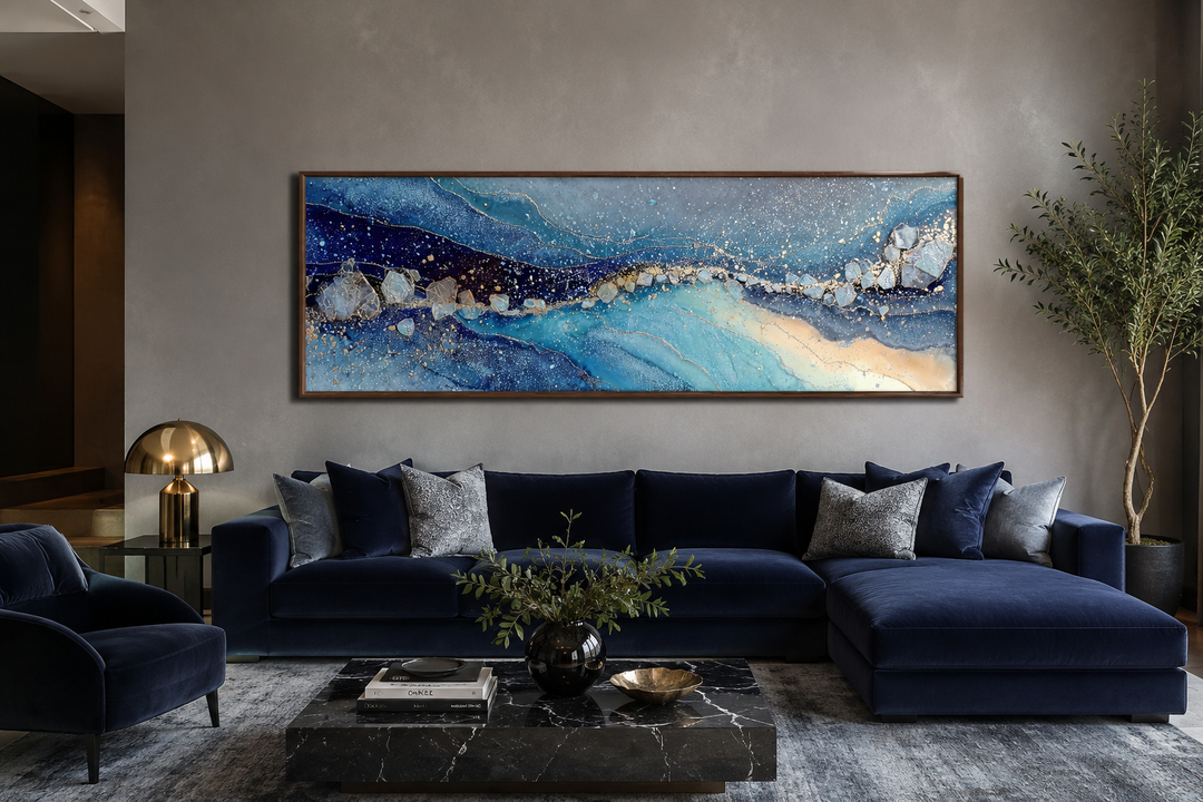 Modern long horizontal blue and navy abstract canvas art hanging above a dark blue velvet sofa.