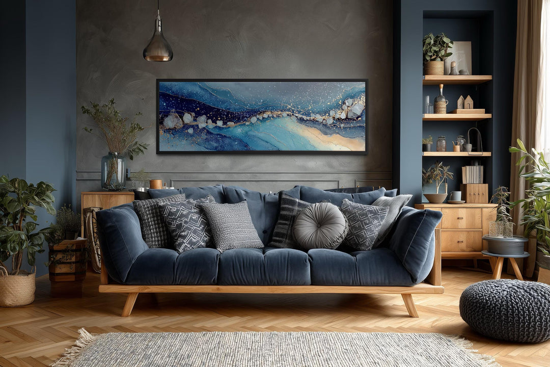 Modern long horizontal blue and navy abstract canvas art above a dark blue sofa in a living room.