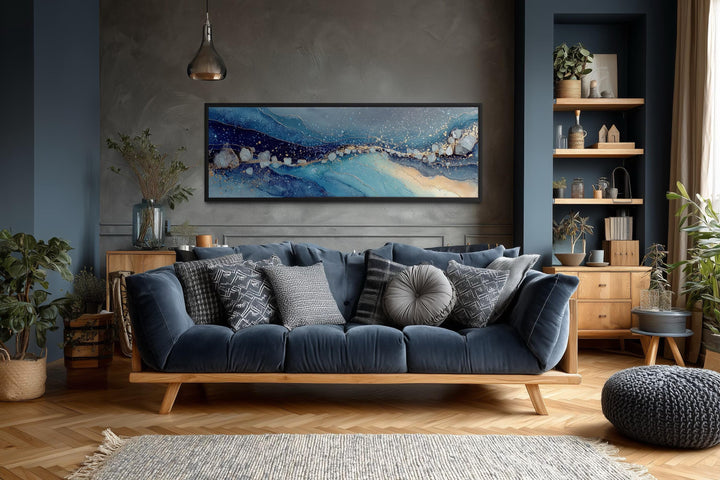 Modern long horizontal blue and navy abstract canvas art above a dark blue sofa in a living room.