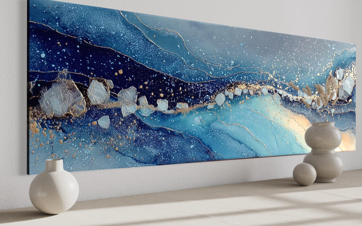Modern long horizontal abstract canvas art with navy and blue waves, gold flecks, and stone accents.