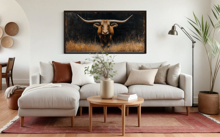 Modern Texas Longhorn Steer in the grass framed farmhouse canvas wall art above a neutral sofa.