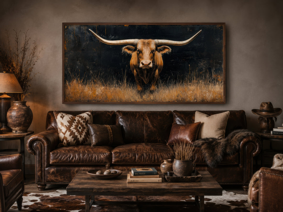 Modern Texas Longhorn steer in grass framed farmhouse canvas wall art above a brown leather sofa.