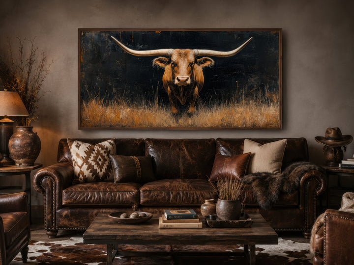 Modern Texas Longhorn steer in grass framed farmhouse canvas wall art above a brown leather sofa.