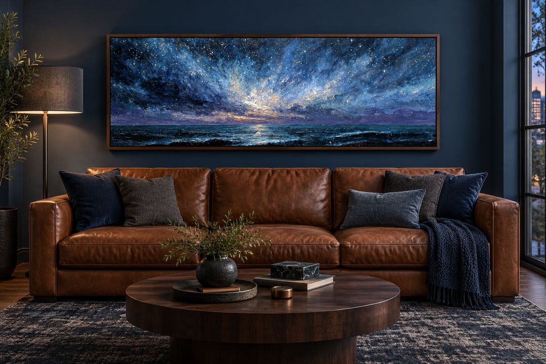 Panoramic blue and purple moody seascape painting in a walnut frame above a brown leather sofa.