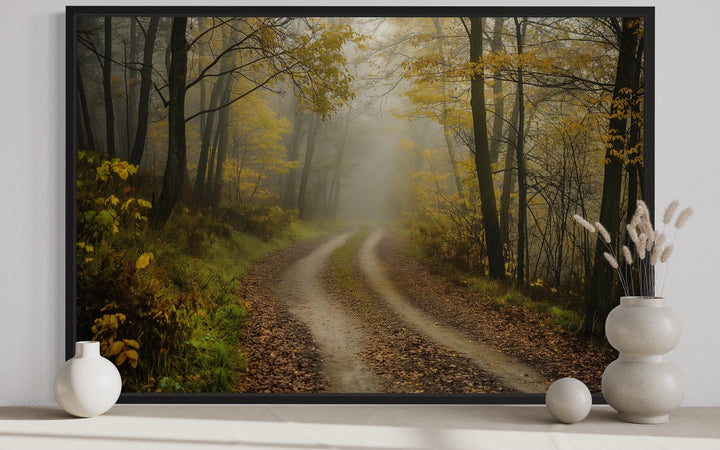 Moody foggy autumn forest framed canvas wall art featuring a misty dirt road through yellow trees.