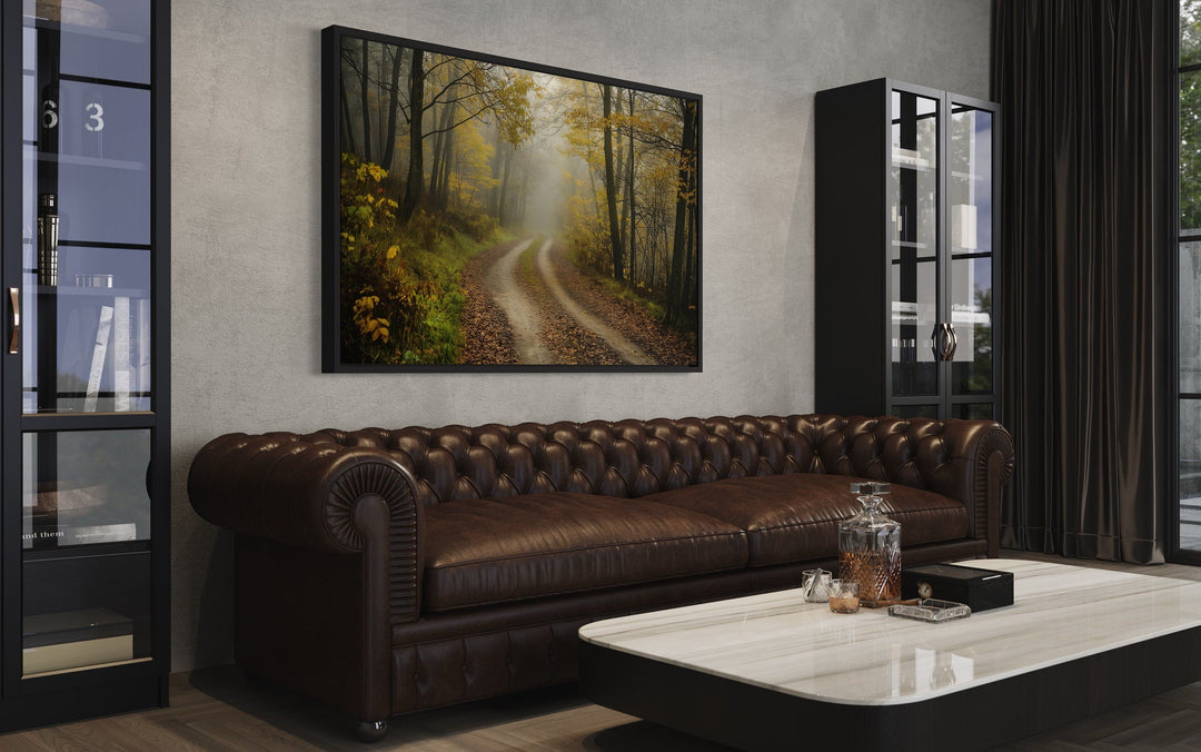 Moody Foggy Autumn Forest Framed Canvas Wall Art hanging above a brown leather chesterfield sofa.