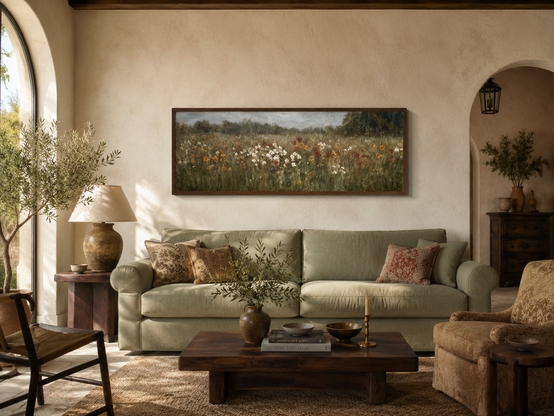 Moody muted wildflower field landscape in a long horizontal frame above a green sofa.