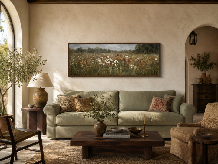 Moody muted wildflower field landscape in a long horizontal frame above a green sofa.