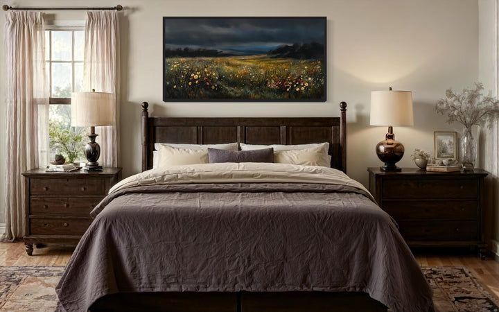 Moody wildflowers meadow at night canvas wall art hanging above a dark wood bed in a bedroom.