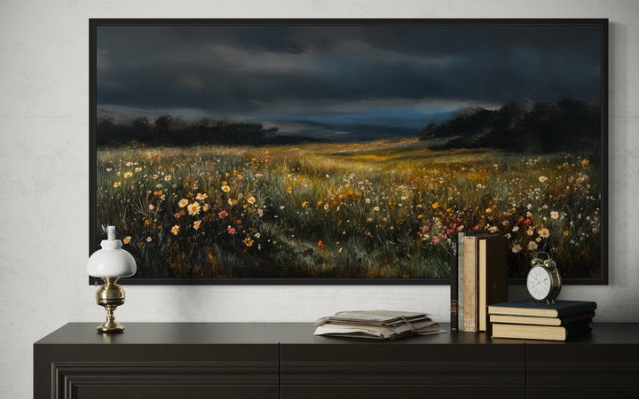 Moody wildflowers meadow at night canvas wall art in a black frame above a dark wood dresser.