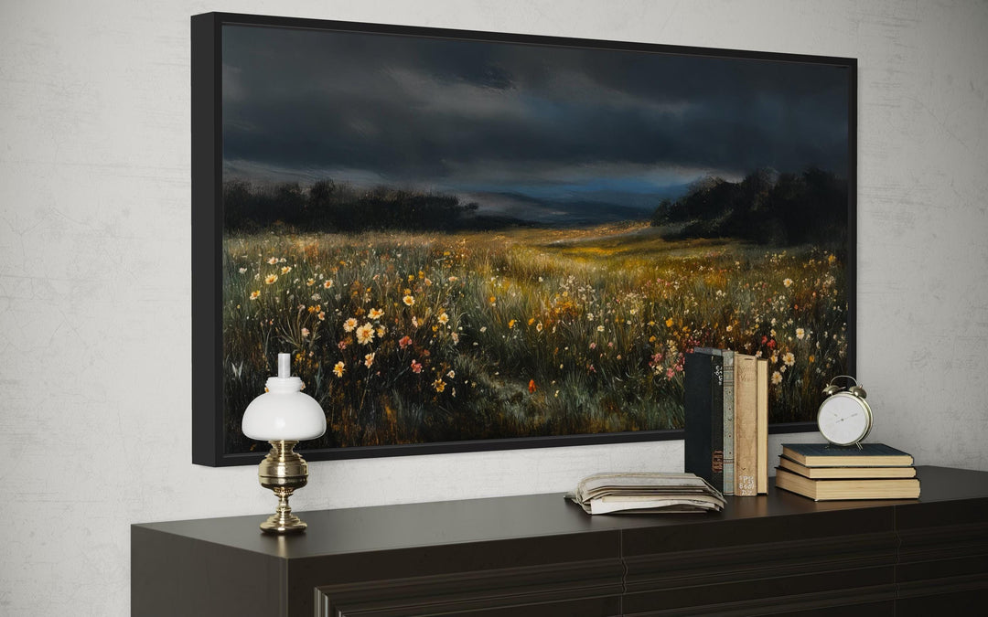 Moody wildflowers meadow at night canvas wall art in a black frame above a dark wood dresser.