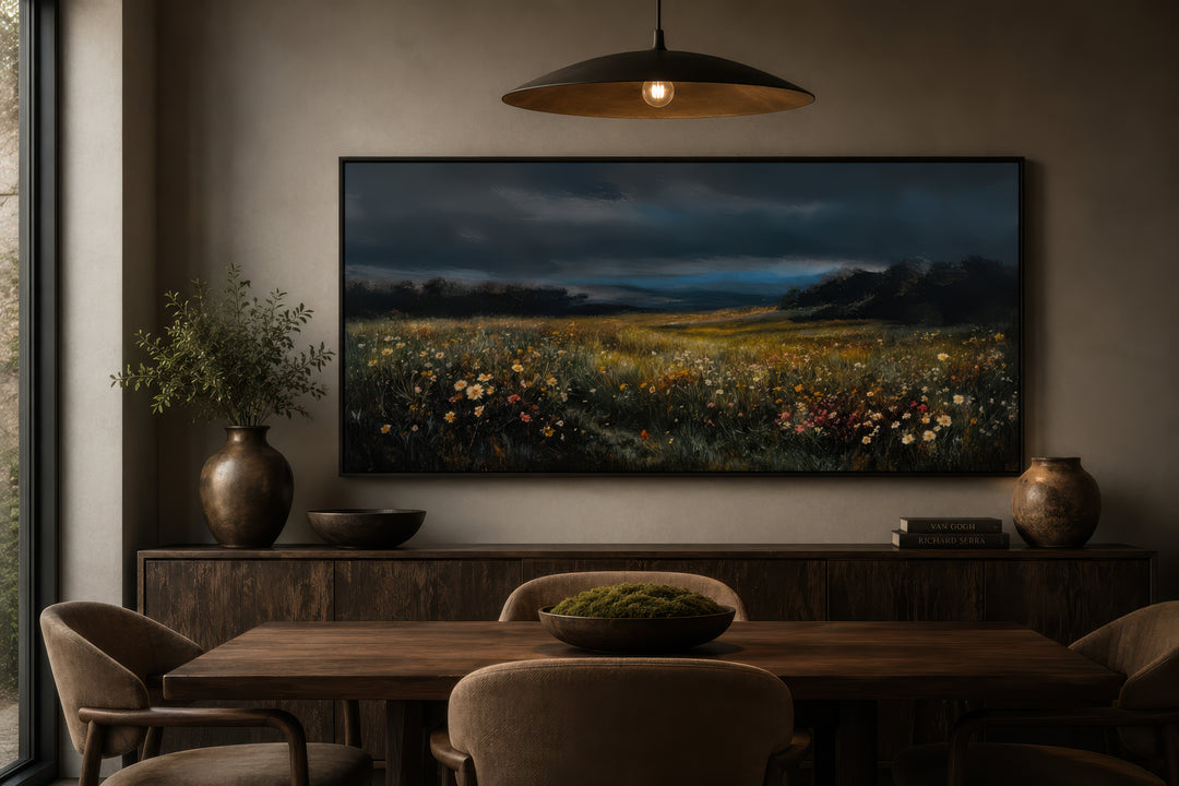 Moody wildflowers meadow at night canvas wall art in a dark frame above a wooden sideboard.