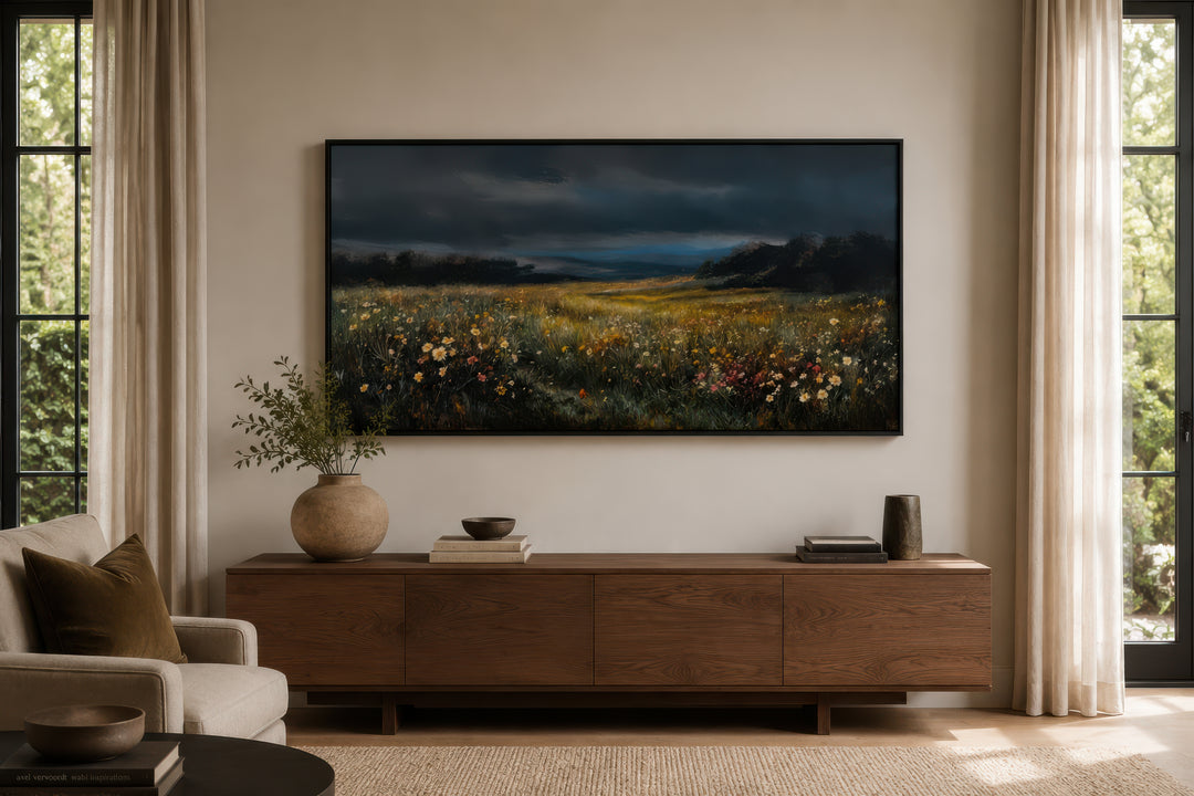 Moody wildflowers meadow at night canvas wall art in a black frame above a wooden sideboard.