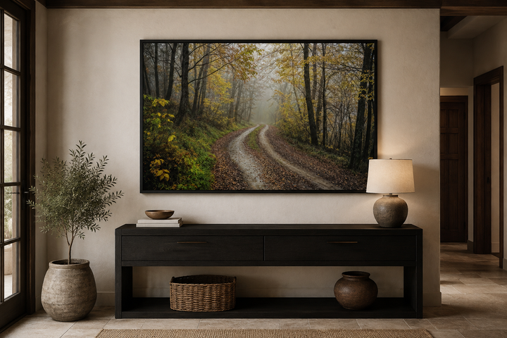Moody foggy autumn forest framed canvas wall art hanging above a dark wood console table.