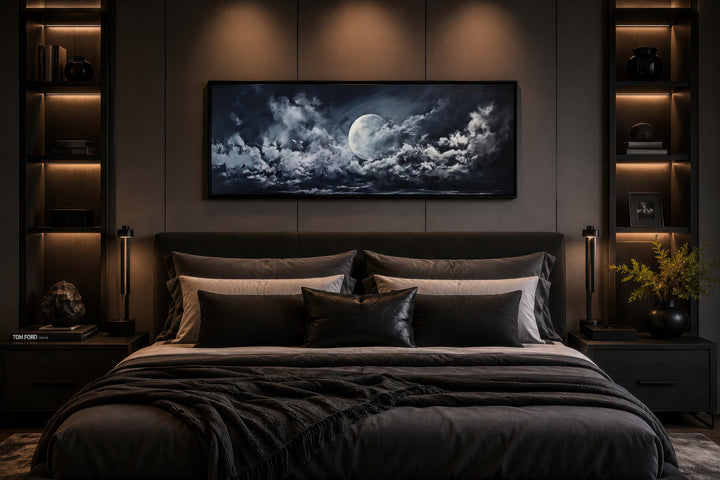 Moon and cloudy sky horizontal framed canvas wall art hanging above a bed in a dark bedroom.