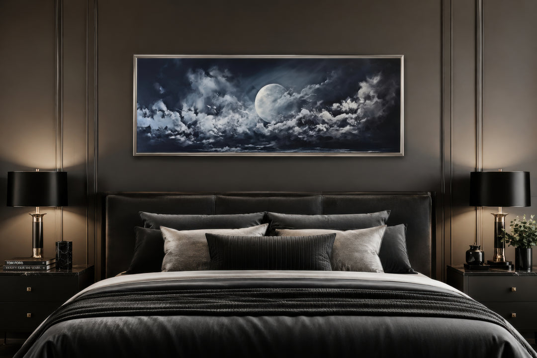 Moon and cloudy sky horizontal framed canvas wall art hanging above a bed in a dark bedroom.