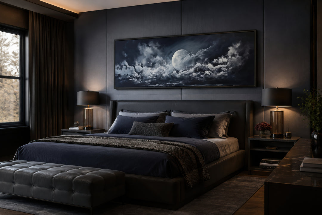 Horizontal framed canvas wall art of a moon and cloudy sky hanging above a bed in a dark bedroom.