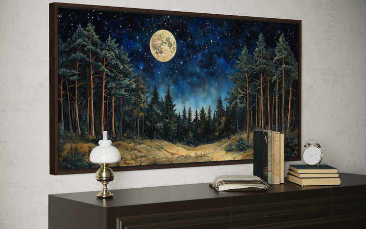 Horizontal wall art of a moonlit pine forest with a starry sky above a dark wood dresser.