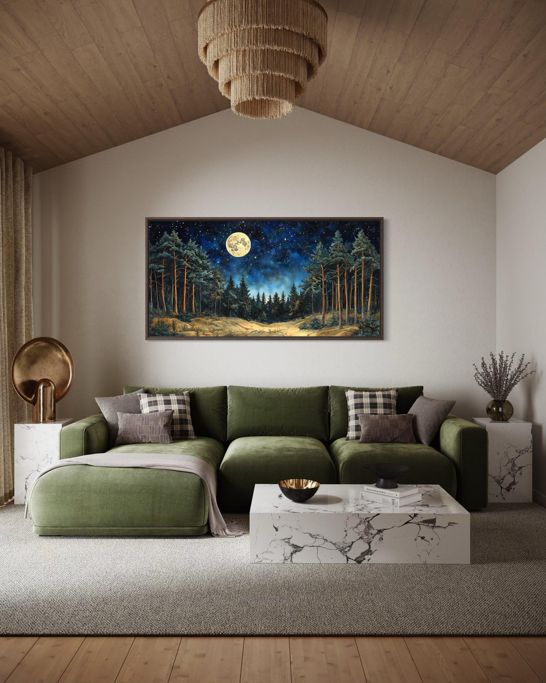 Horizontal wall art of a moonlit pine forest above a green sofa in a modern rustic living room.