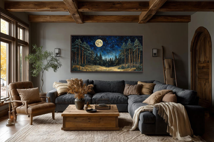 Horizontal canvas art of a moonlit pine forest hanging in a rustic living room with wood beams.