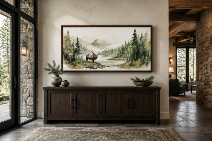 Moose in wilderness watercolor framed canvas wall art above a dark wood sideboard in a cabin.